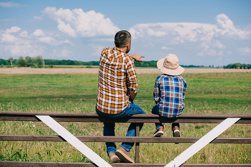 father and son looking out at open field. Learn more about Rural home loans.