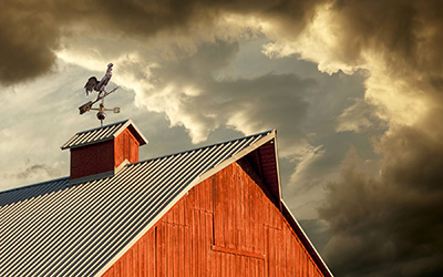 stormy sky with weather vane on top of barn